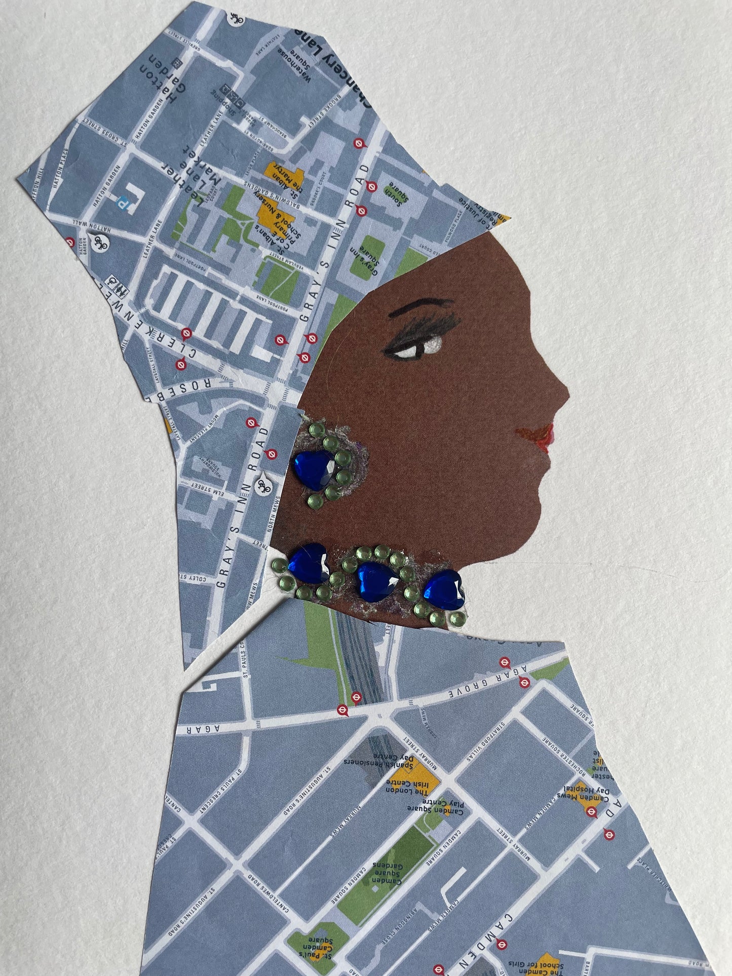 This card depicts a woman named Holborn Heather. She is wearing a matching blouse and hat that have a map print design. She also wears blue and green earrings and necklace to match with the map print colours.