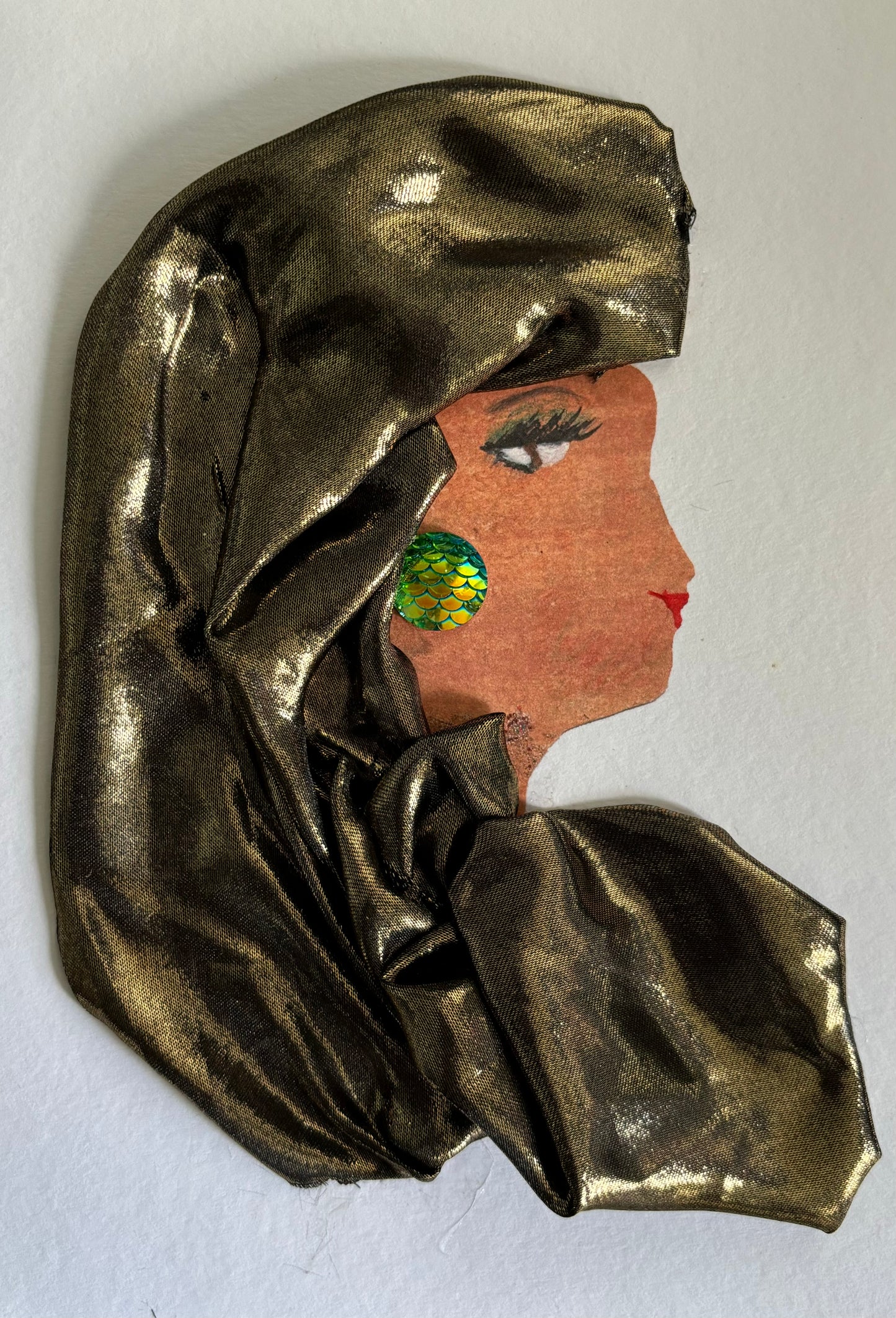 I designed this card of a woman named Fairlop Fallon. Her hair is covered by a gold head scarf that is draped across her shoulder. She wears a top with the same gold color, styled with a green, fish-scaled earring on her right ear.