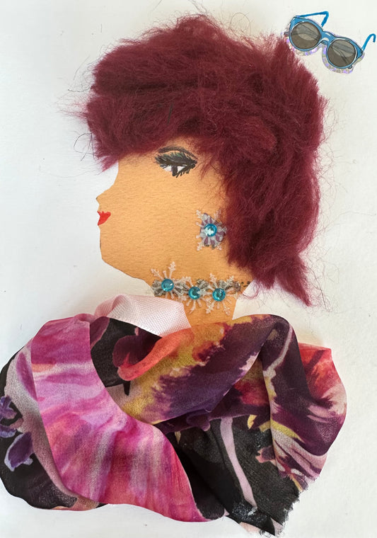 I designed this handmade card of a woman named Gloucester Gail. She is dressed in a pink and purple patterned chiffon blouse. She has a snowflake shaped earring and necklace which match the colour of the blue and white sunglasses.