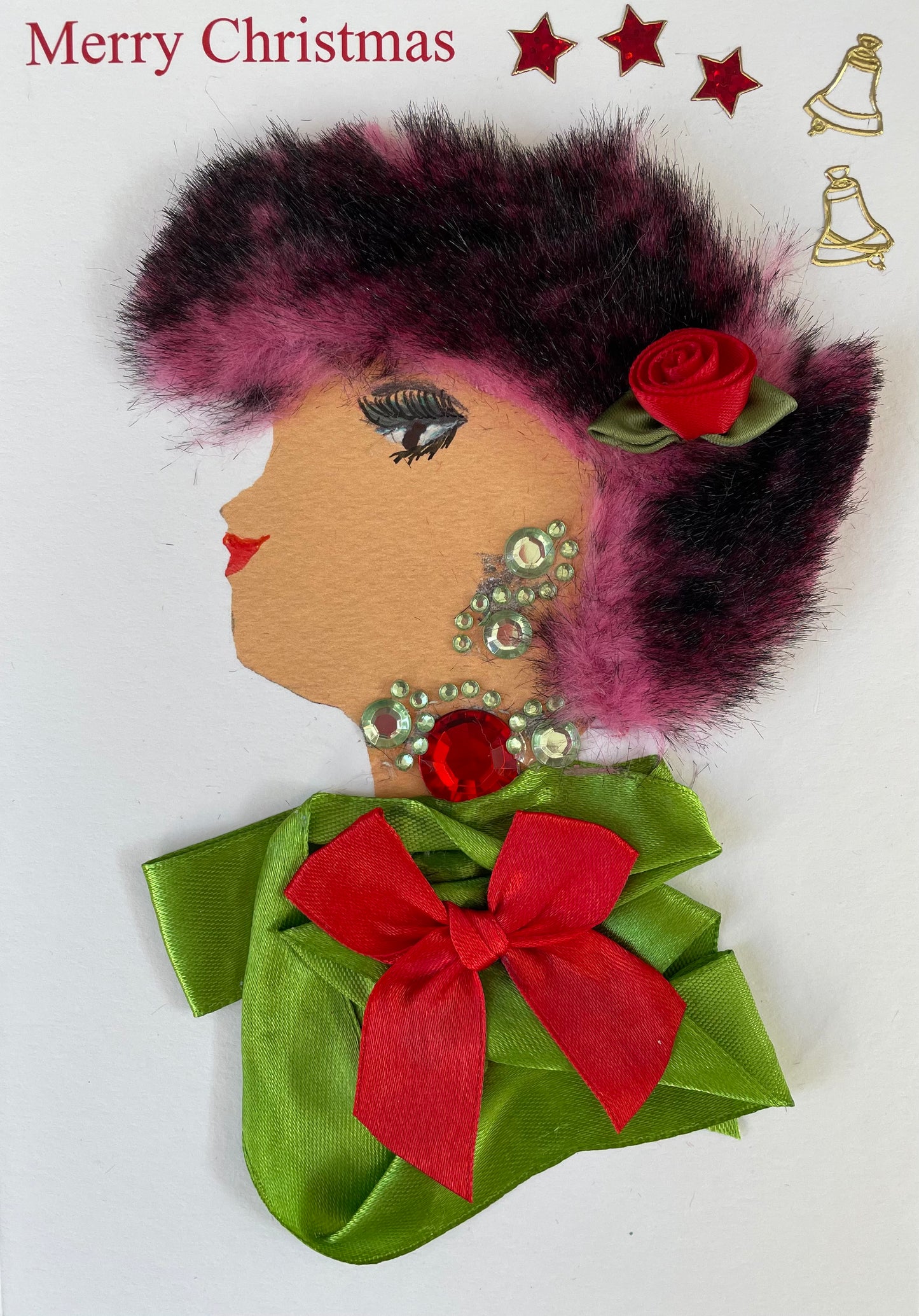 I designed this card of a woman named Ellie Edgware. She has a white skin tone and is wearing a lime green blouse with a red bow on it. She has diamanté earrings and a necklace with a red jewel. There is a red rose flower in her pink and black hair! To the left of her, it says "Merry Christmas". To the right of her, there are 3 red stars with 2 gold bells.