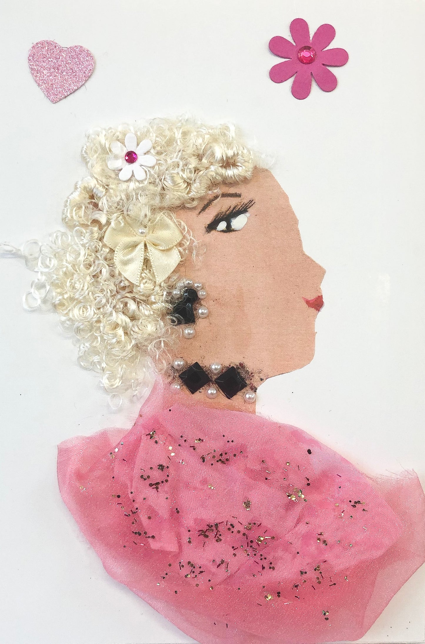 This card has been given the name Pink Pimlico. The card shows a woman wearing a pink shimmery blouse, Black diamond shaped gem jewellery, and she has blonde hair with a tan bow in it. In the top left corner, there is a pink glittery heart, and in the top right corner, there is a pink flower with a pink gem in the center.