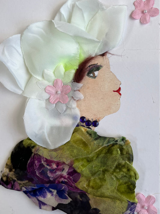 This card is called Regan. She wears a floral print blouse and white petals in her hair. 