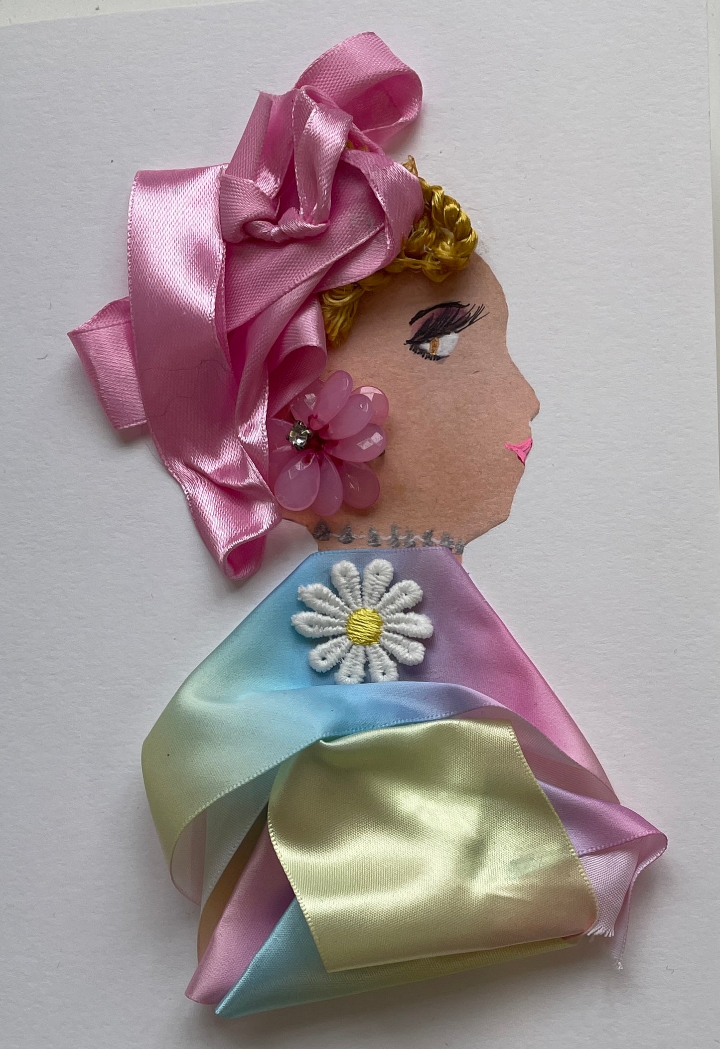 I designed this card for a woman named Doctor Colourful. She wears a ribbon as a blouse which is rainbow-themed, and a white daisy on the front. She wears pink ribbons in her short blonde hair, and a flower gem as her earring.